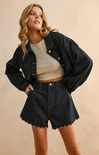 Woman wearing a denim jacket and shorts on a beige background
