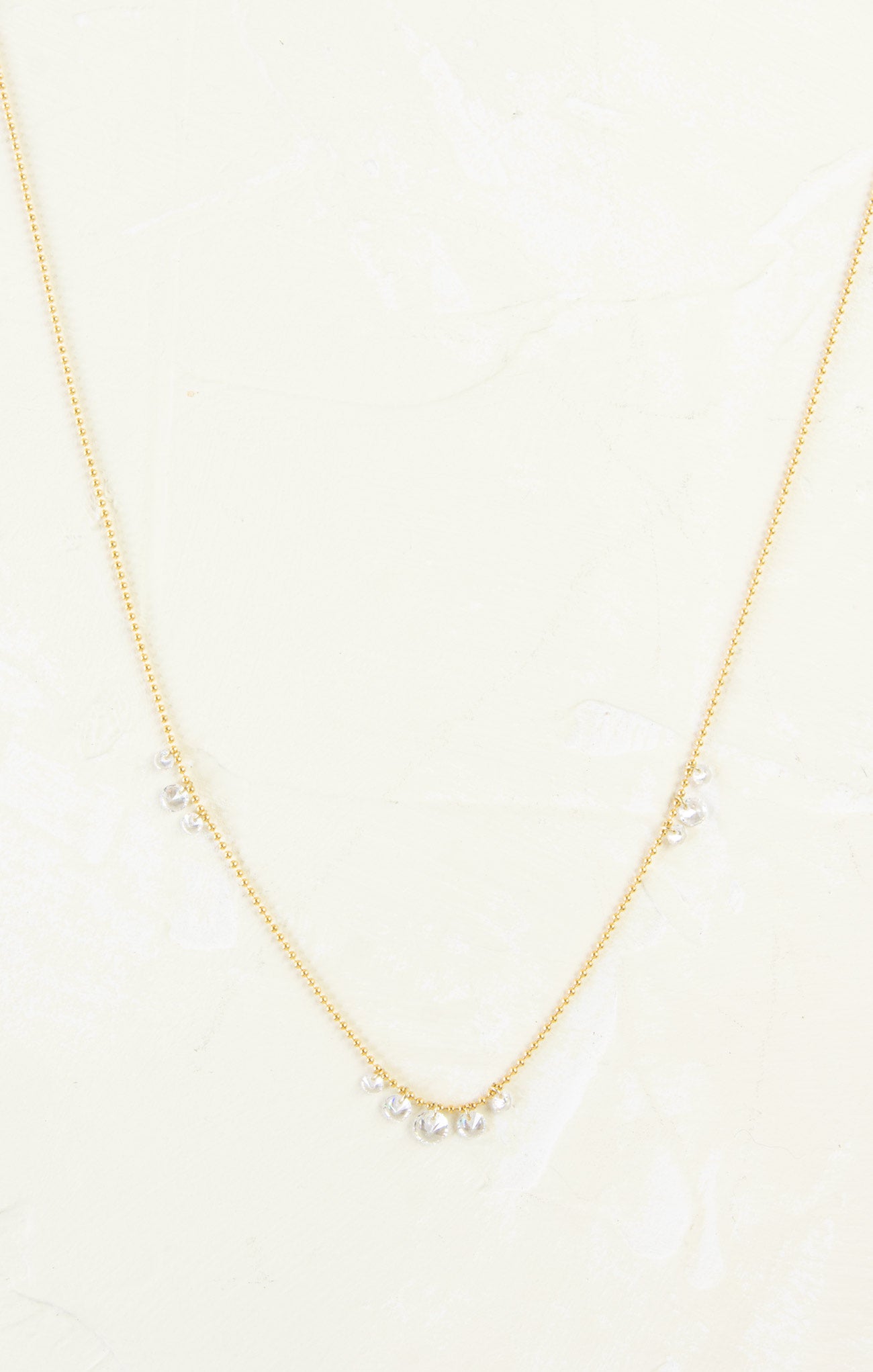 Gold necklace with small pearls on a light beige background