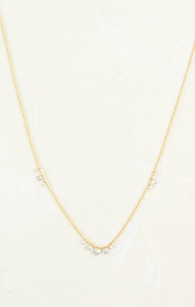 Gold necklace with small pearls on a light beige background