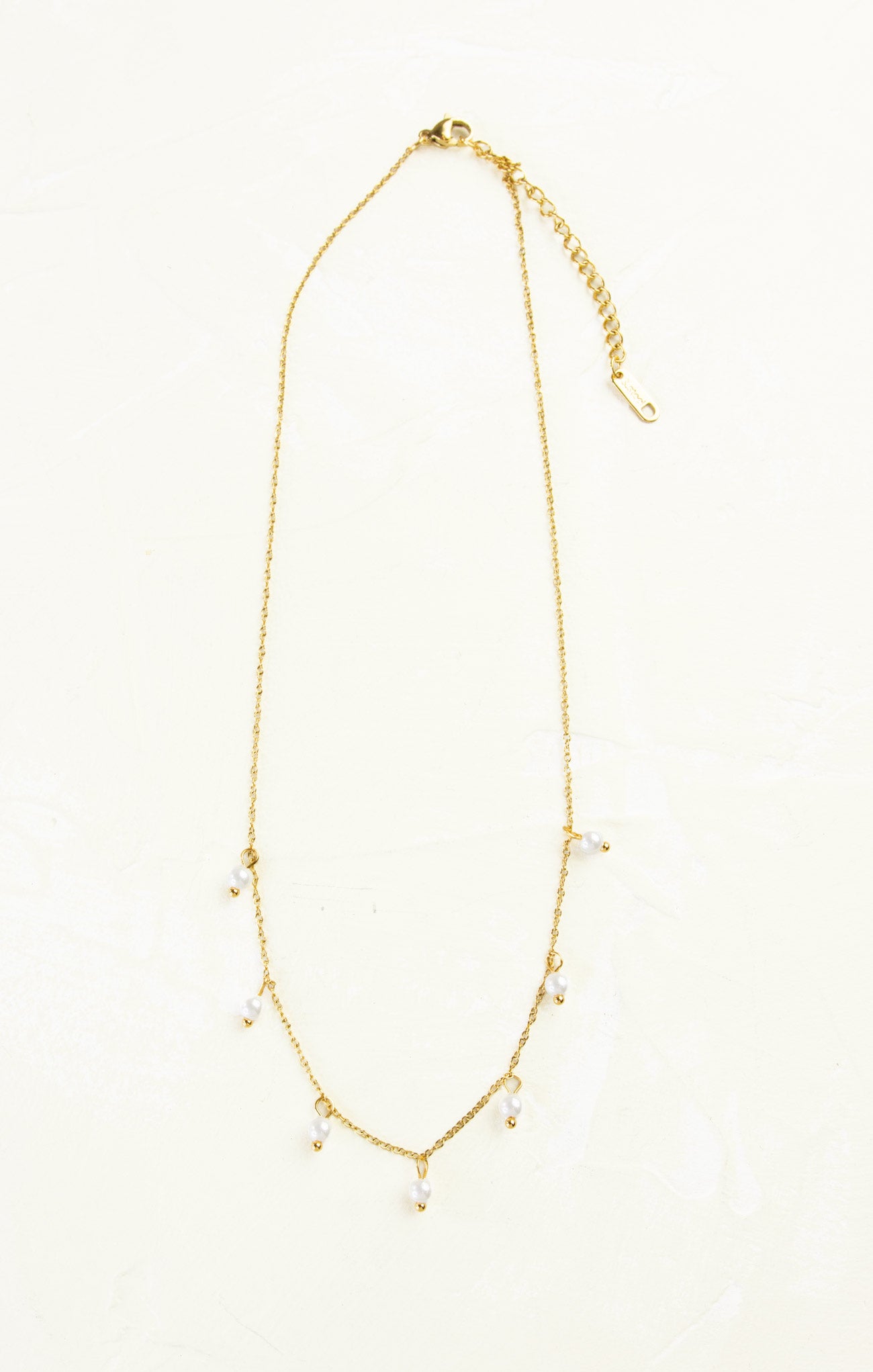 Gold necklace with small beads on a white background