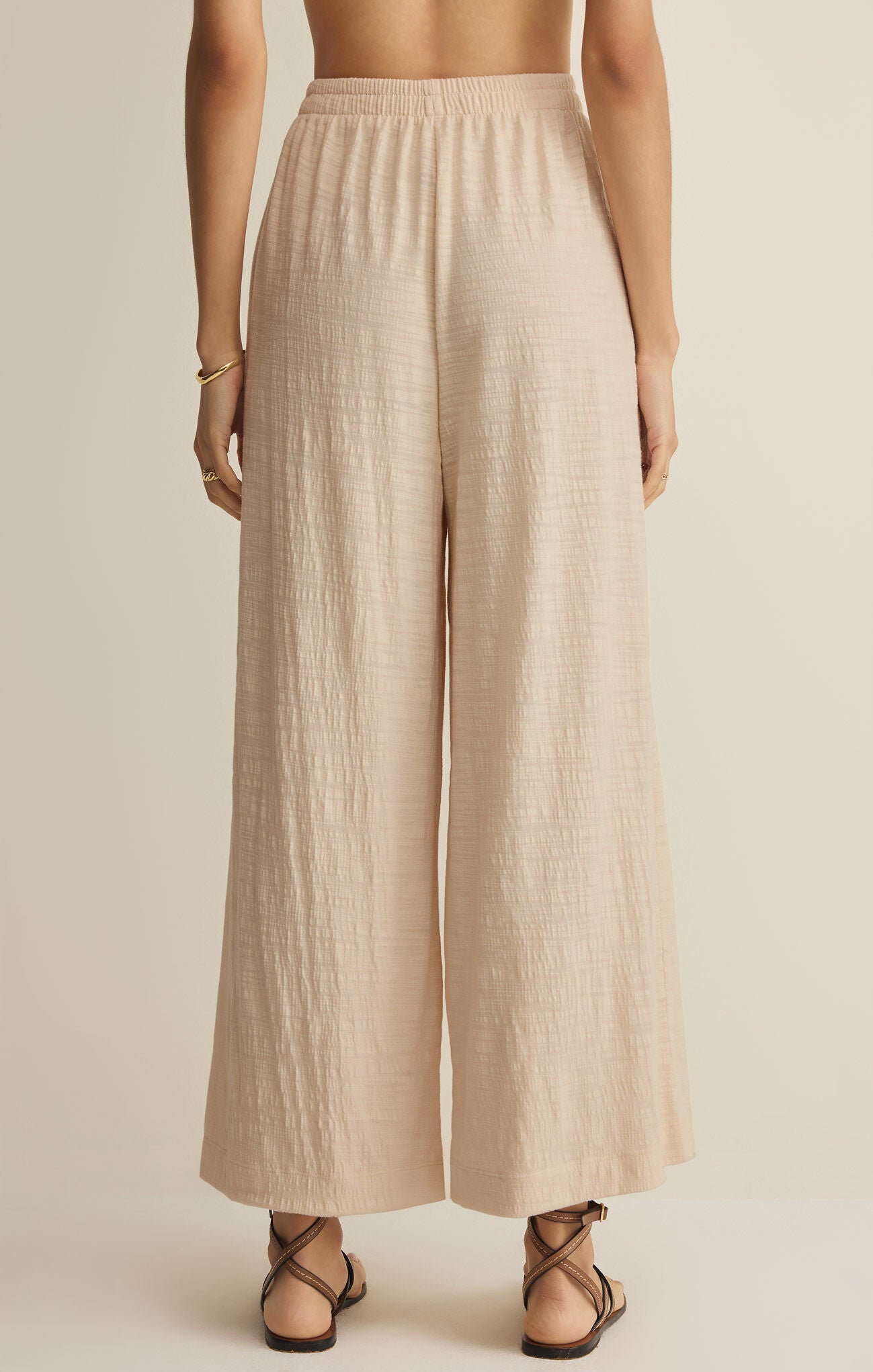 Beige wide-leg pants worn by a person on a beige background