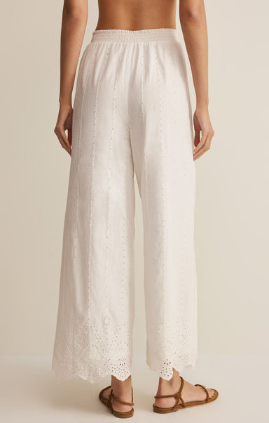 White wide-leg pants with lace trim worn by a person on a beige background