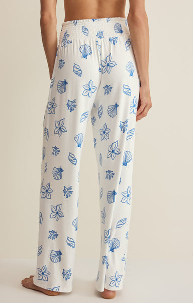 White pajama pants with blue floral pattern worn by a person on a neutral background