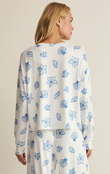Woman wearing a white outfit with blue floral patterns on a beige background