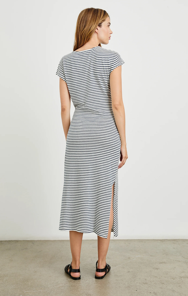 Woman wearing a black and white striped dress with a side slit against a plain background