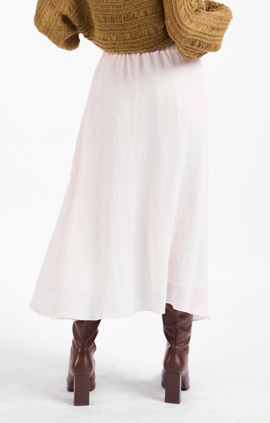 Person wearing a white skirt and brown knee-high boots on a white background