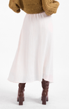 Person wearing a white skirt and brown knee-high boots on a white background