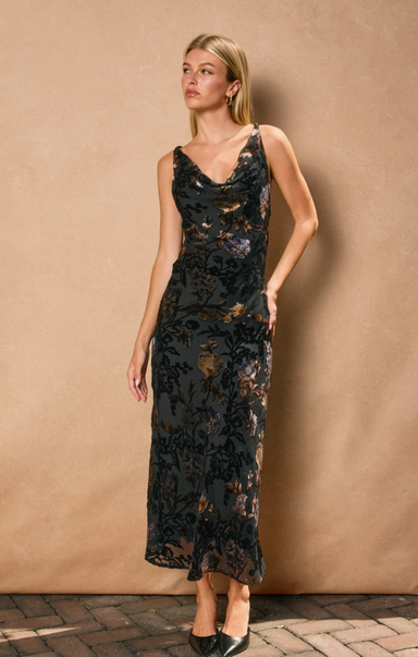 Woman wearing a black lace dress against a beige wall