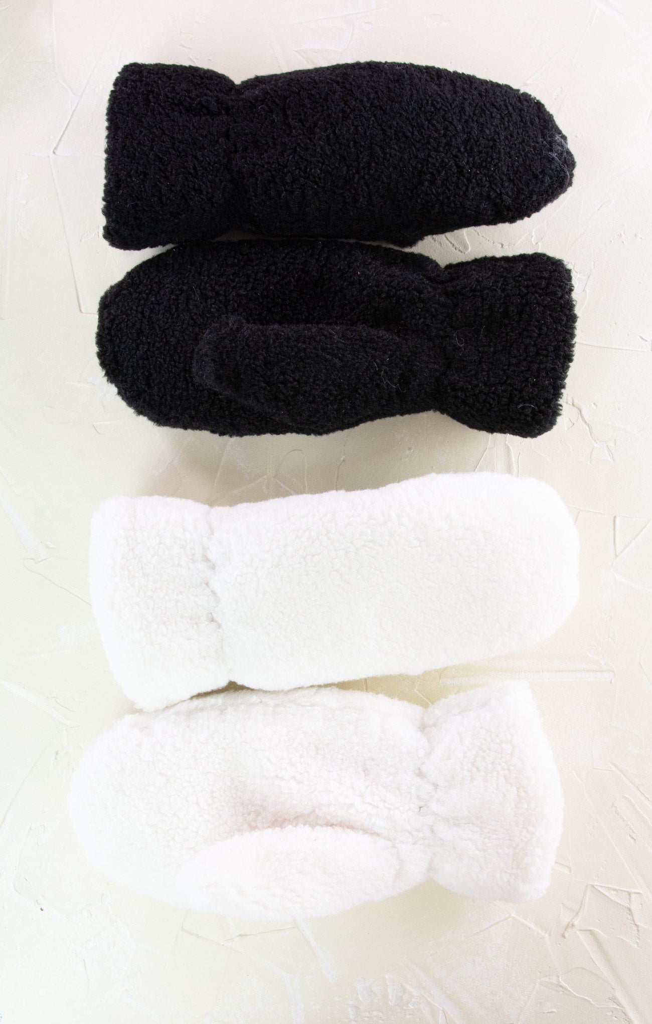 Two pairs of black and white fuzzy socks on a light background