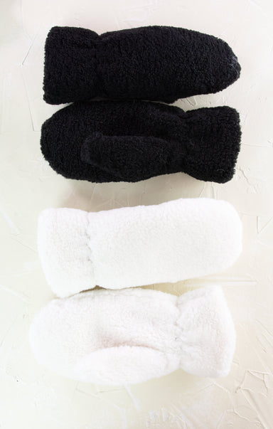 Two pairs of black and white fuzzy socks on a light background