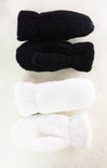 Two pairs of black and white fuzzy socks on a light background