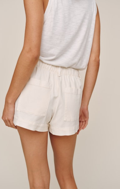 Person wearing white shorts and a white top on a beige background