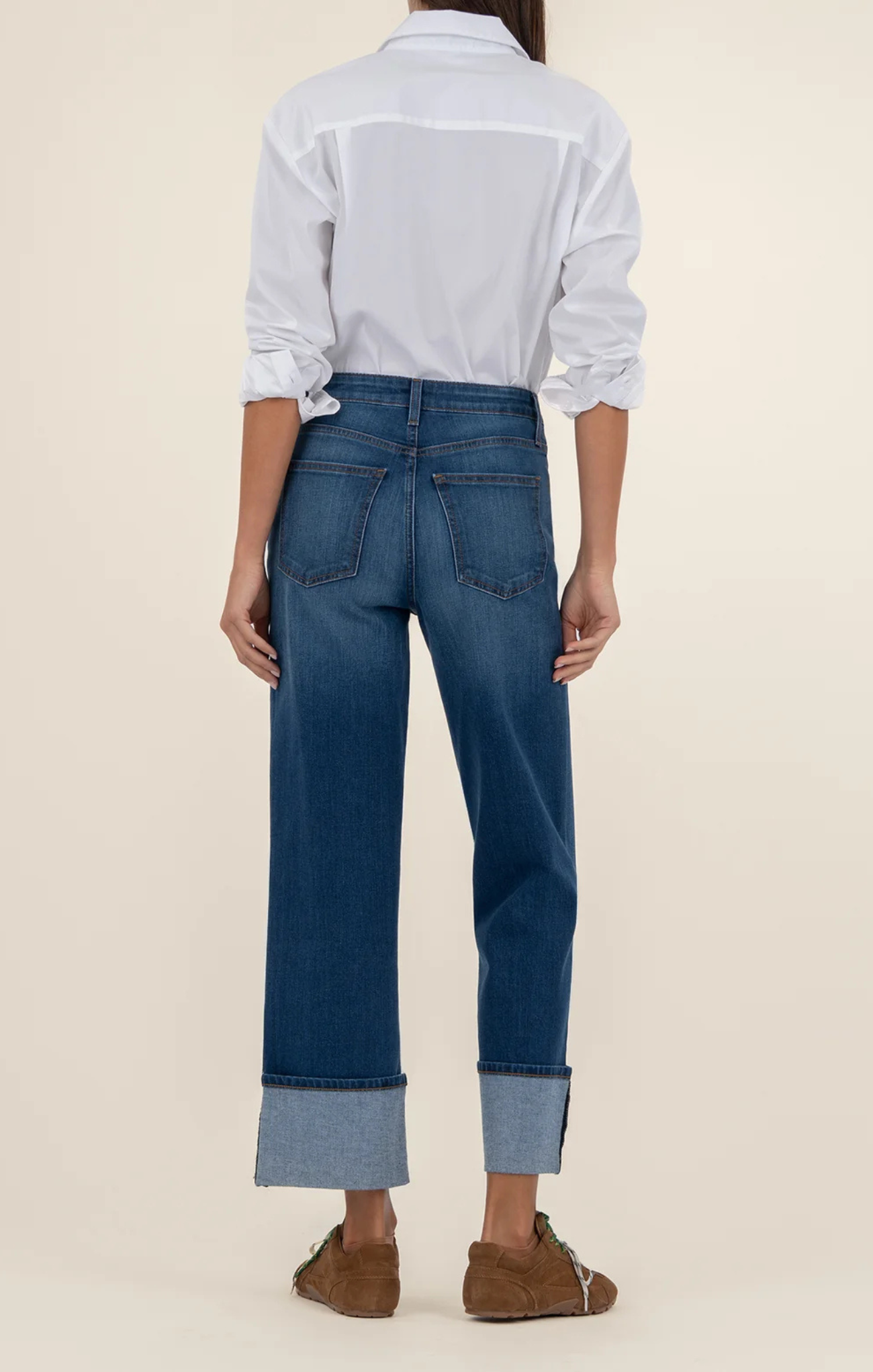 Person wearing blue jeans and a white shirt on a beige background