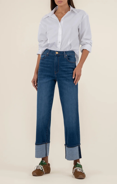 Person wearing a light blue shirt and dark blue jeans on a beige background