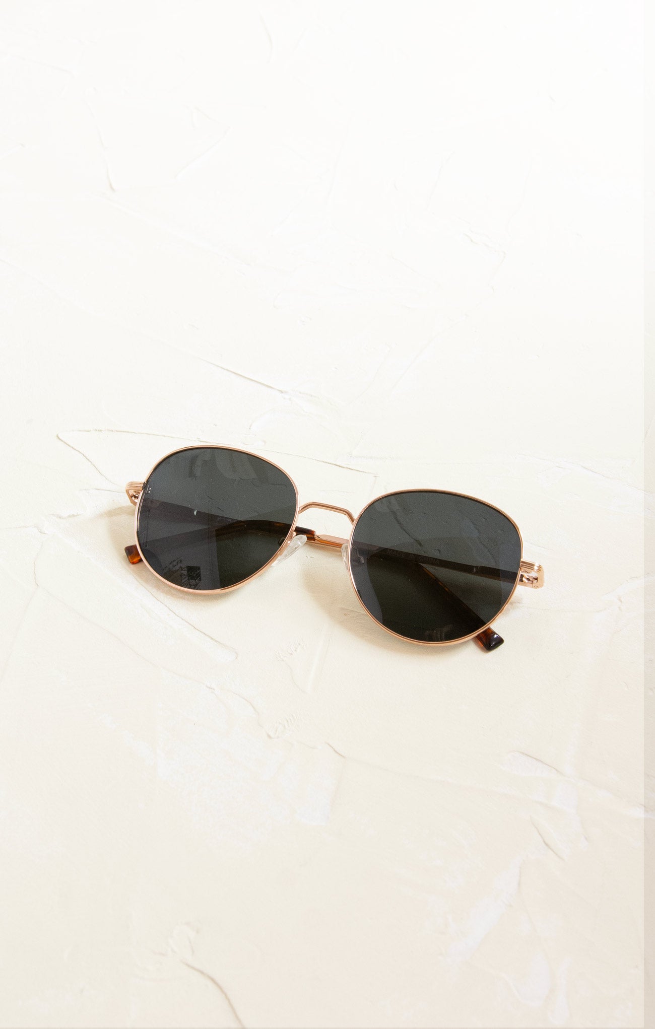 Gold-framed sunglasses with black lenses on a white background