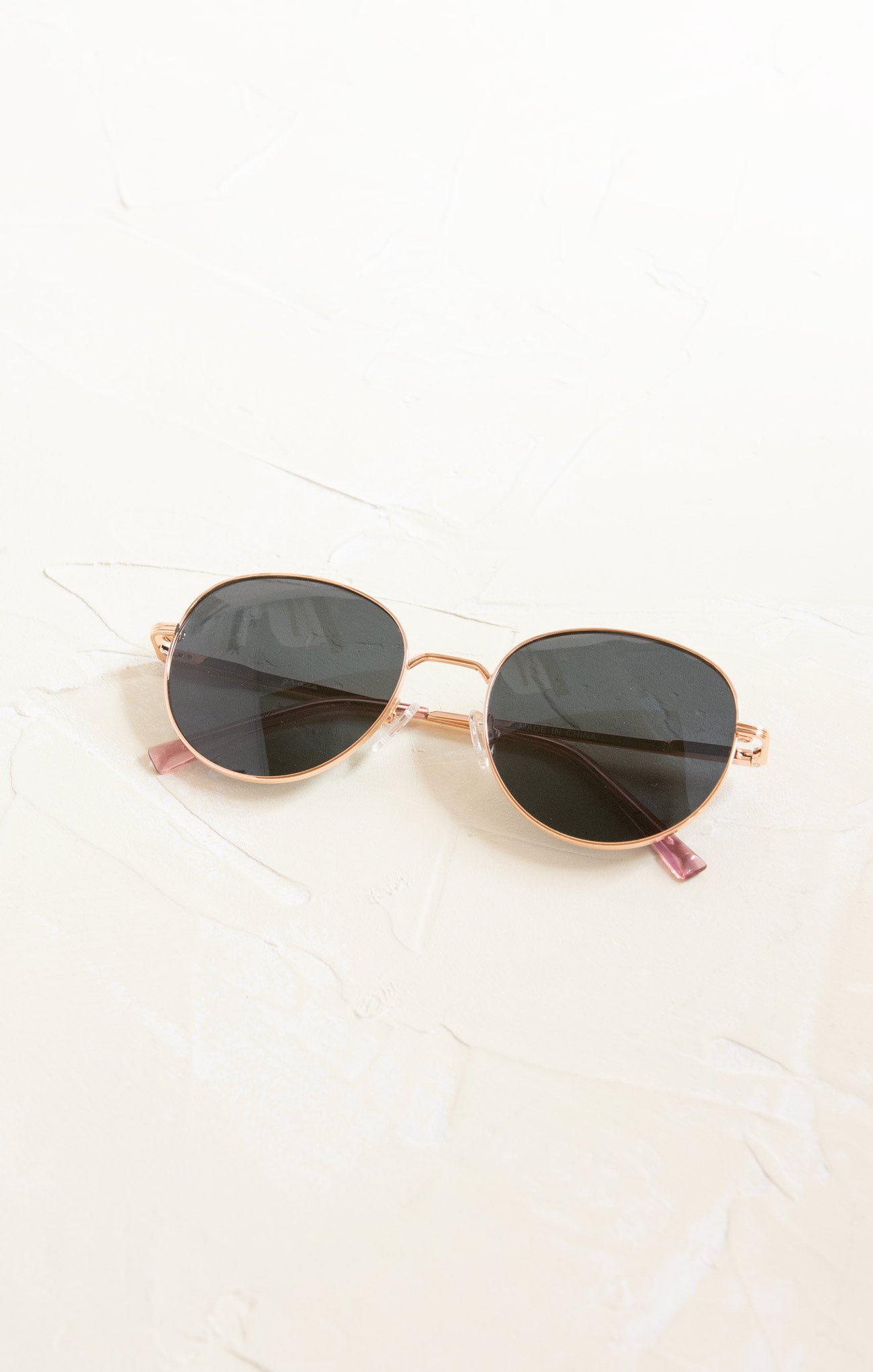 Round sunglasses with gold frame and black lenses on a white background