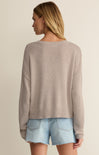 Woman wearing a beige sweater and denim shorts on a plain background