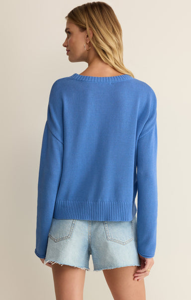 Woman wearing a blue sweater and denim shorts on a beige background