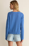 Woman wearing a blue sweater and denim shorts on a beige background