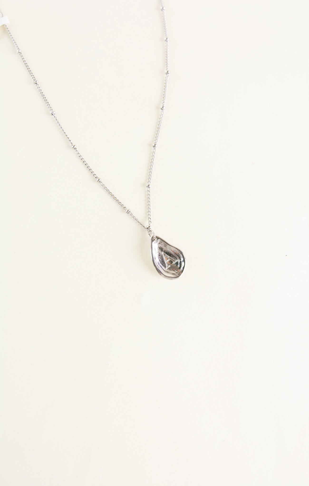 Teardrop-shaped pendant necklace on a white background