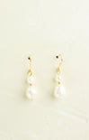 Pair of pearl earrings with gold hooks on a light beige background