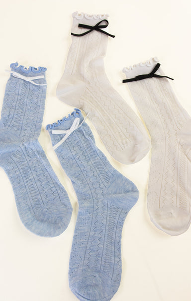 Two pairs of socks, one blue and one white, with decorative bows on a light background.