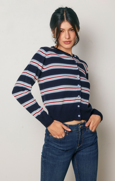 Woman wearing a navy striped sweater and blue jeans against a plain background