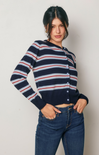 Woman wearing a navy striped sweater and blue jeans against a plain background