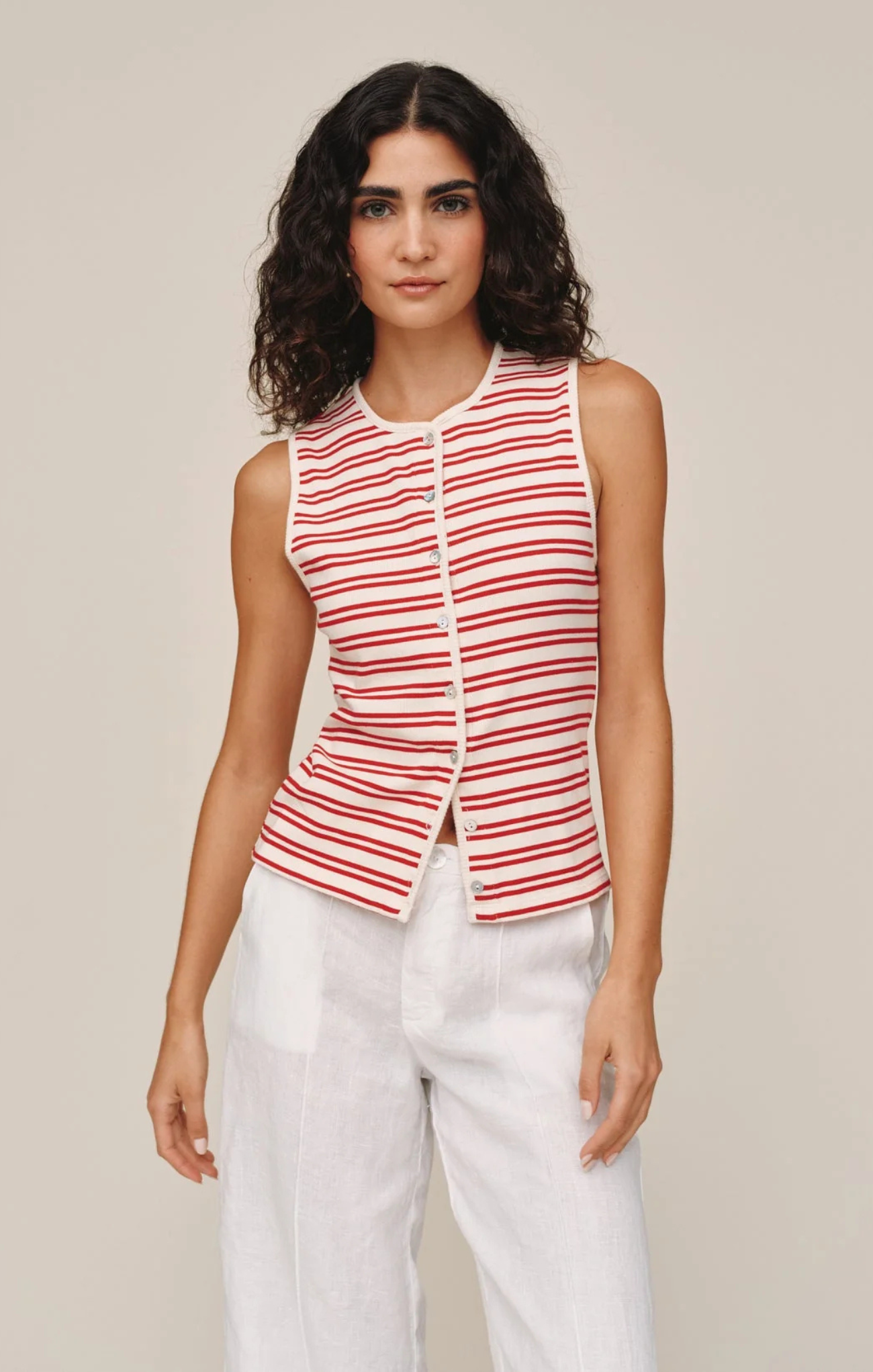 Woman wearing a red and white striped sleeveless top with a beige background