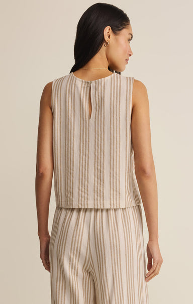 Woman wearing a beige and white striped sleeveless top and pants on a plain background