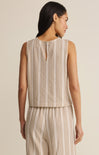 Woman wearing a beige and white striped sleeveless top and pants on a plain background