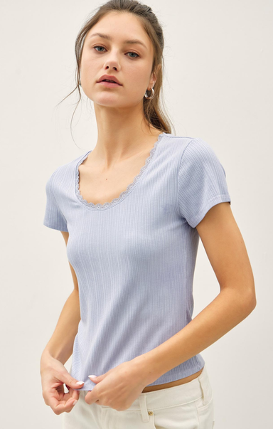 Woman wearing a light blue ribbed knit top against a plain background