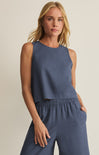 Woman wearing a blue sleeveless top and pants against a beige background