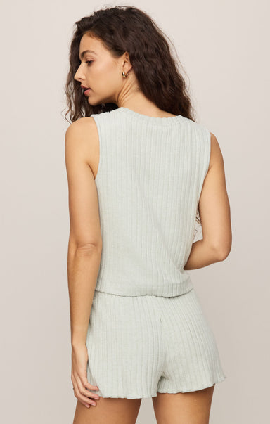 Woman wearing a light green ribbed sleeveless top and shorts set on a beige background