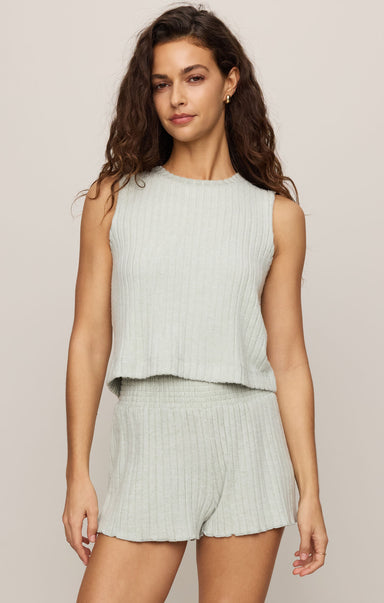 Woman wearing a light green sleeveless top and shorts set on a plain background