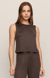 Woman wearing a brown sleeveless top and pants on a beige background