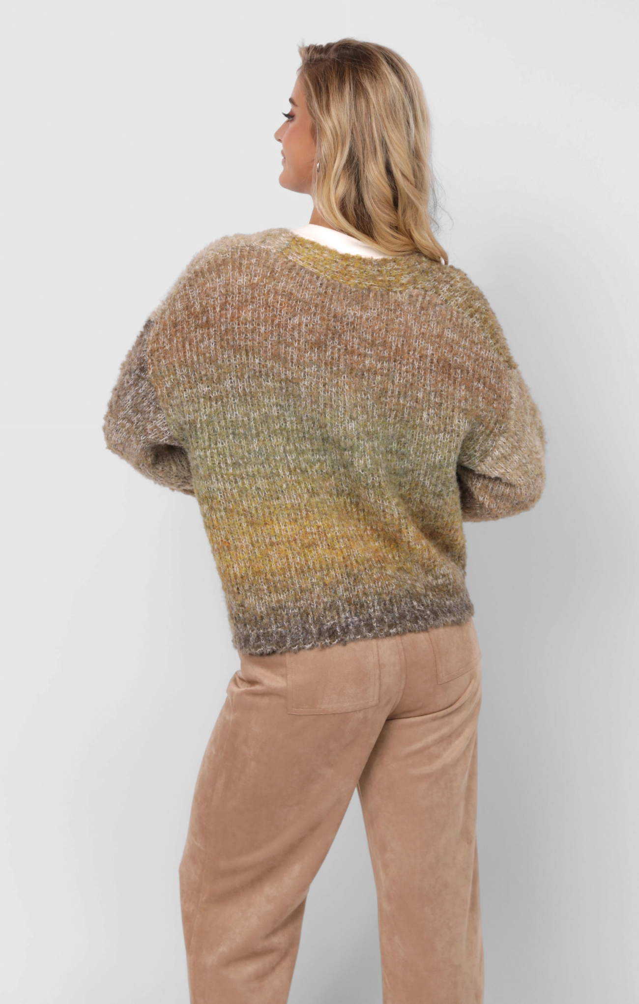 Person wearing a gradient sweater and beige pants on a white background