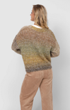 Person wearing a gradient sweater and beige pants on a white background