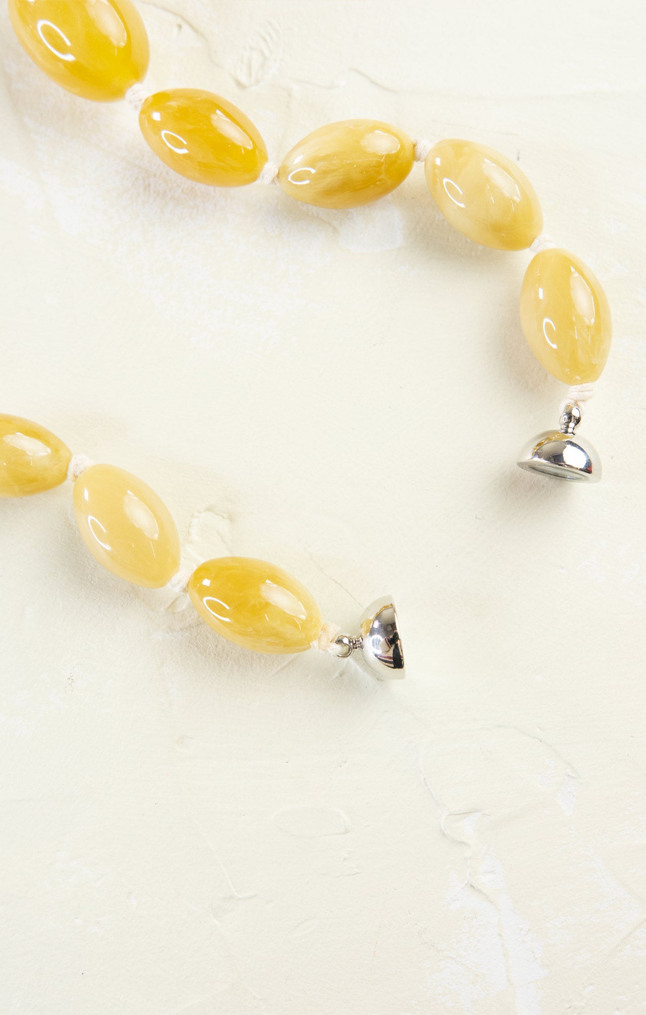Yellow beaded necklace with silver clasp on a white background
