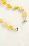 Yellow beaded necklace with silver clasp on a white background