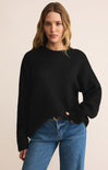 Woman wearing a black sweater and blue jeans on a beige background