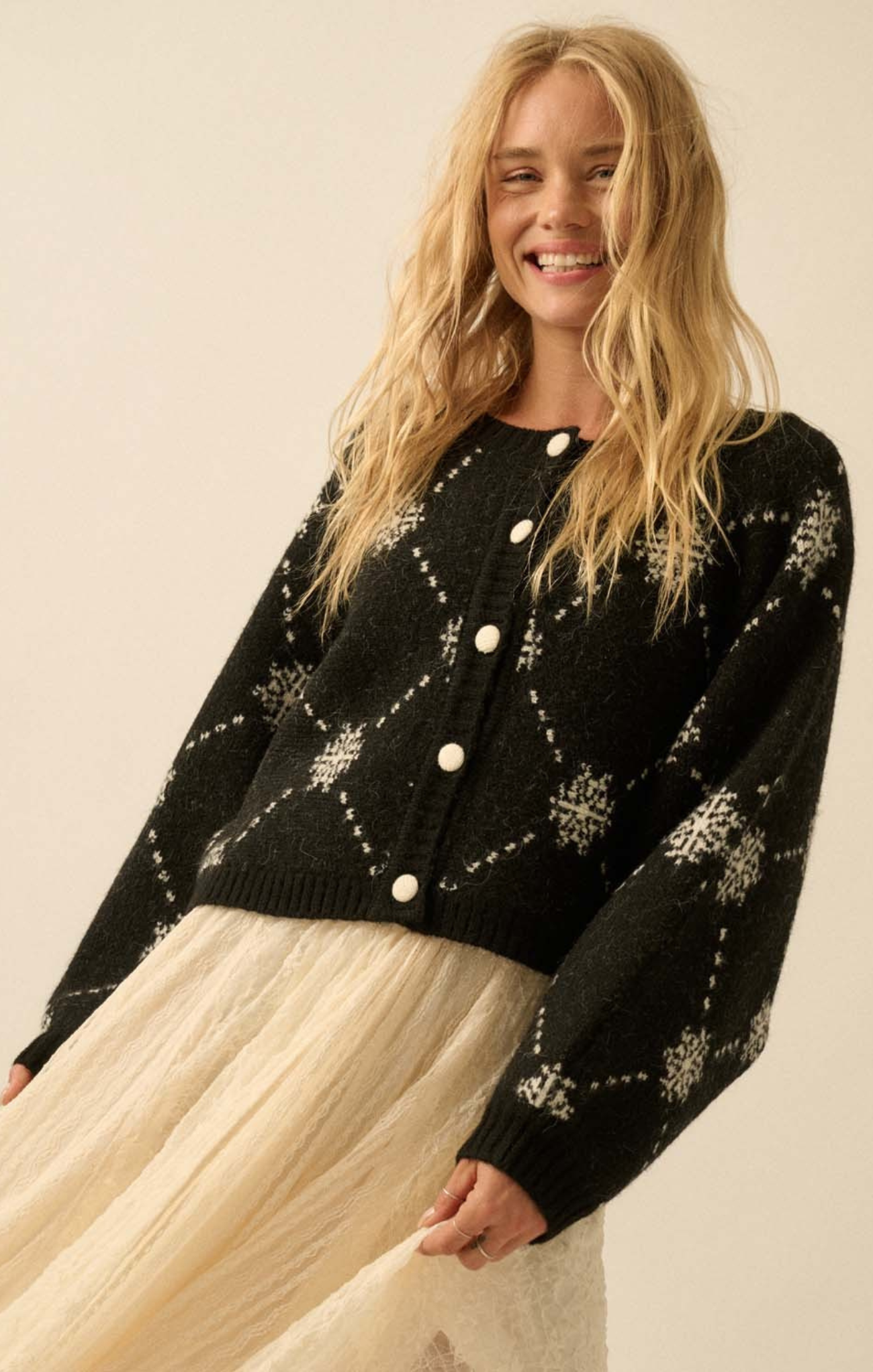 Woman wearing a black cardigan with white patterns on a beige background