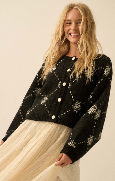 Woman wearing a black cardigan with white patterns on a beige background