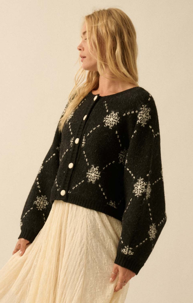 Woman wearing a black knitted cardigan with white patterns on a beige background