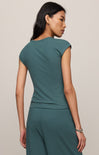 Woman wearing a teal outfit against a beige background