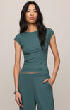 Woman wearing a teal outfit against a neutral background