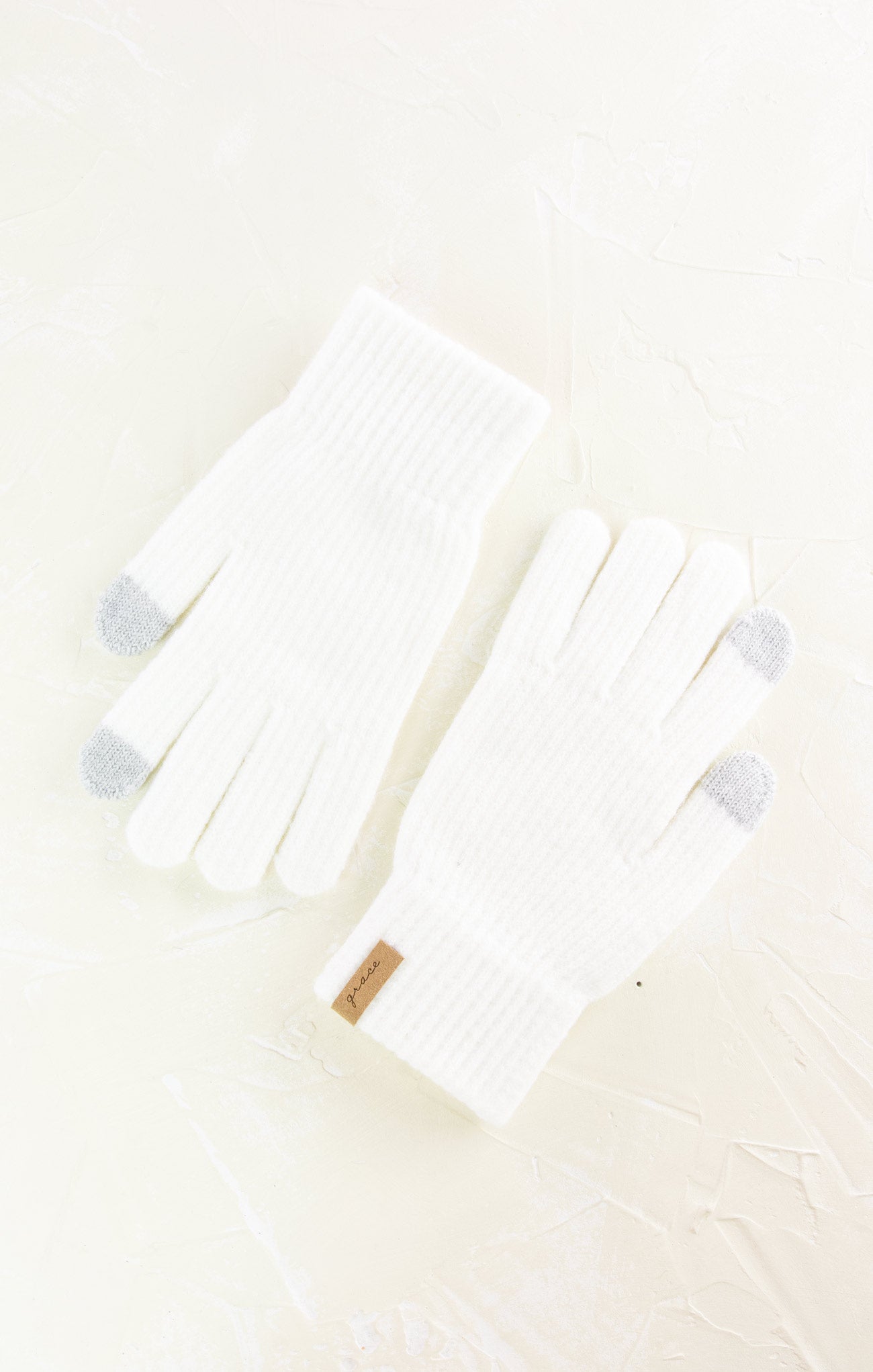 White baby outfit with gray accents on a light beige background