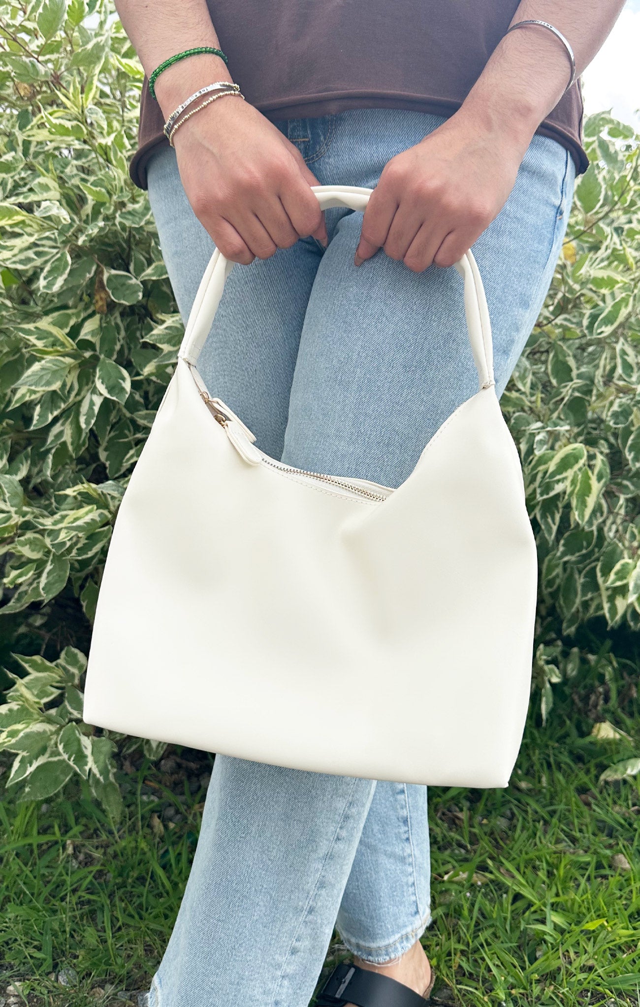 Person holding a white handbag with a blurred green background