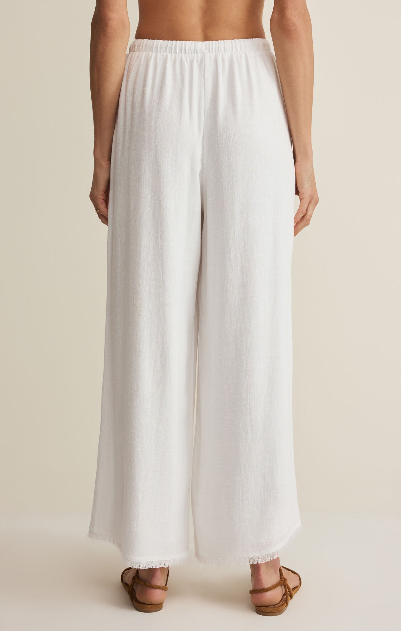 White wide-leg pants worn by a person on a beige background