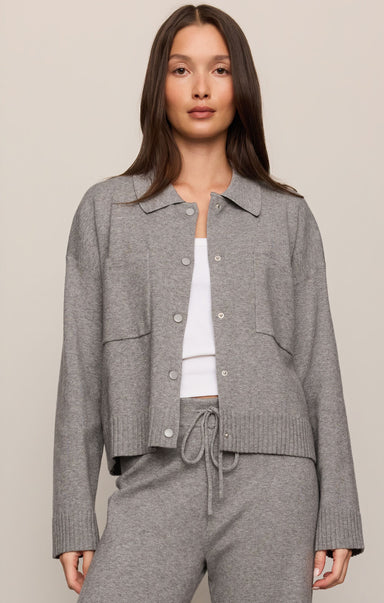 Woman wearing a gray textured jacket over a white top and gray pants on a beige background